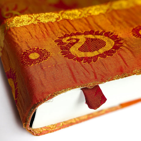 Close-up of an orange fabric with embroidered patterns on a white background