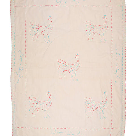 Pink quilt with embroidered dragonfly designs on a white background
