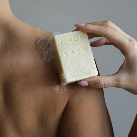 Persoon gebruikt Food for Skin Body Bar op de rug onder de douche.
