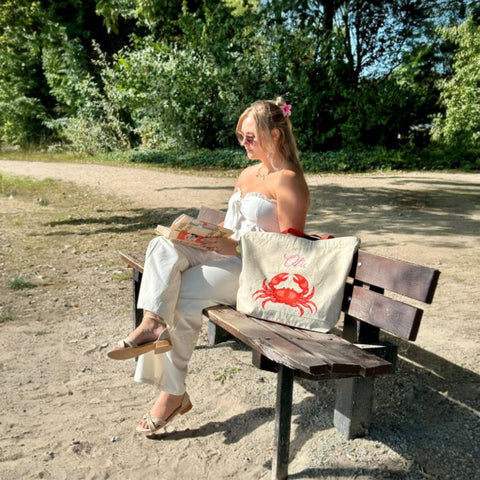 Duurzame tas gerecycled katoen sfeerfoto met model buiten op bankje bij het strand