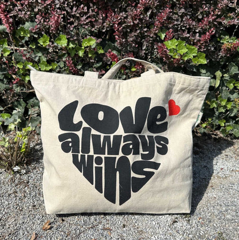 Duurzame met hart van gerecycled katoen tekst Love Always Wins foto buiten op grindpad