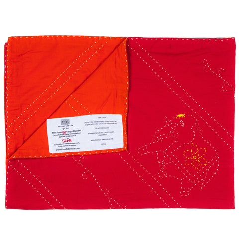 Red quilt with white stitching and a label on a white background