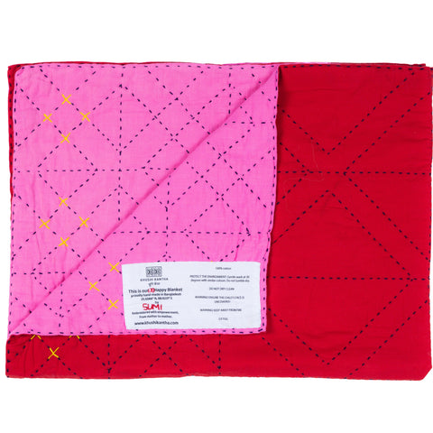 Pink and red quilt with a visible brand label on a white background
