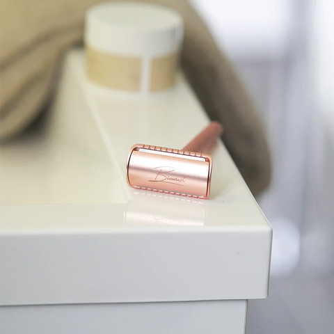 Safety razor rose gold op de rand van de wastafel.