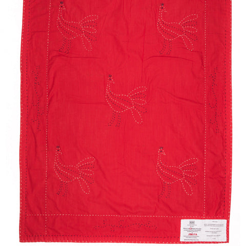 Red quilt with embroidered birds on a white background