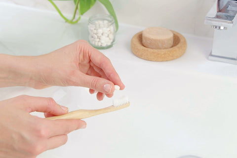 bamboo toothbrush for adults from beewise medium bristles being used on a sink at the bathroom with toothpaste tablets