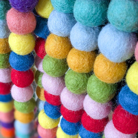 Close-up of colorful felt ball garland with various colors.