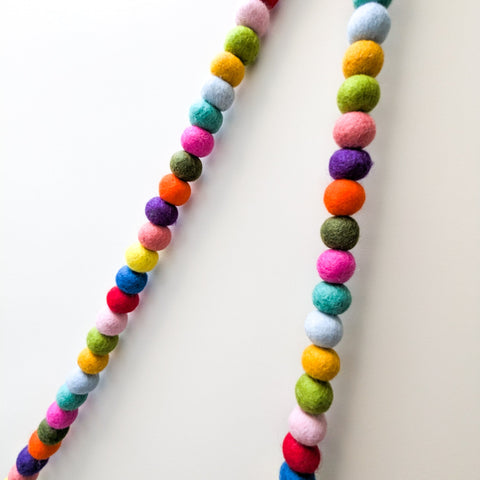 Colorful felt ball necklace on a white background
