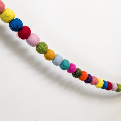 colourful felt ball garland on white background