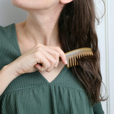 sandalwood comb handmade with a nice design anti static being used by a woman to comb her hair