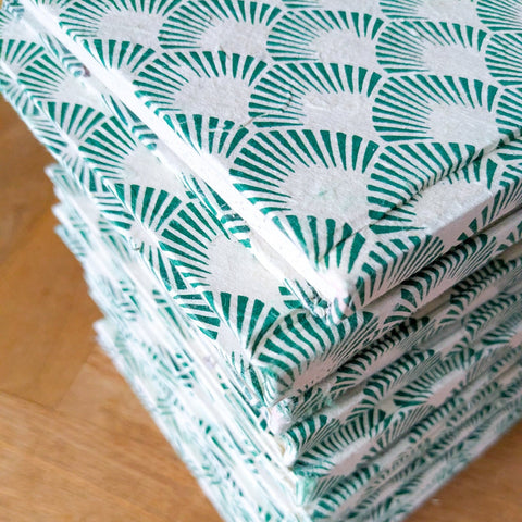 stack of recycled paper notebooks on wooden surface