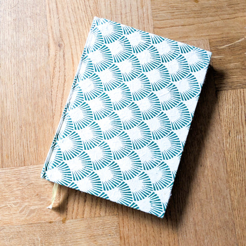 Green and white patterned book on a wooden surface