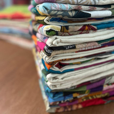 Stack of folded sari patchwork cushion covers on a brown wooden table