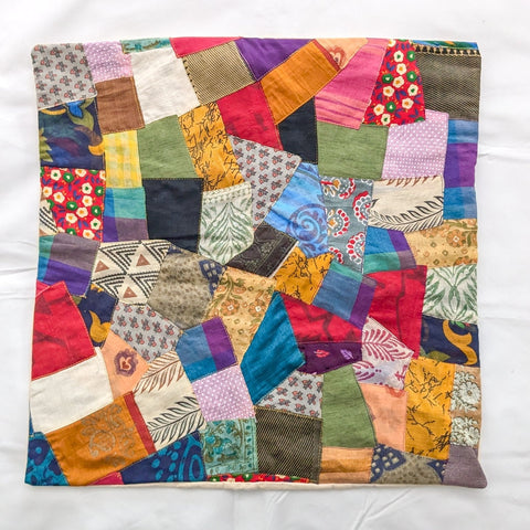 Colourful sari patchwork cushion cover laying flat on a white surface