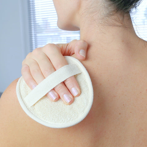 Loofah pad sponge made of natural plant showing being used by a woman to wash her back