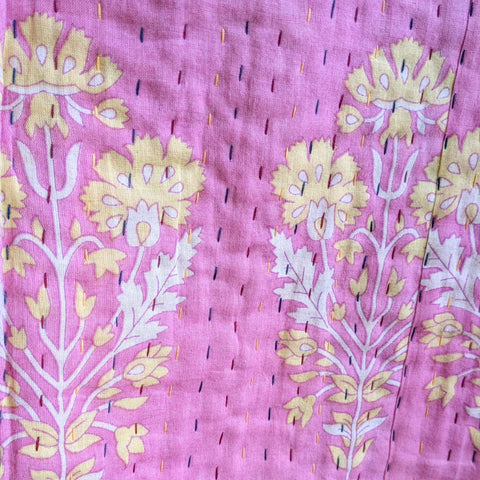 Floral patterned fabric with yellow and white flowers on a pink background