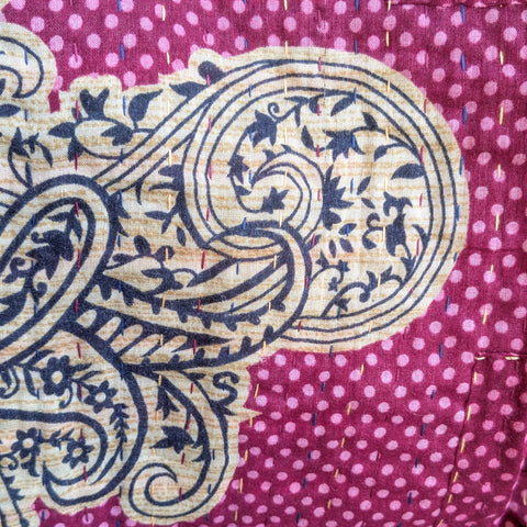 Close-up of a fabric with paisley pattern on a pink polka dot background