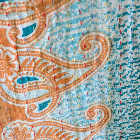 Close-up of a patterned fabric with orange and blue designs.