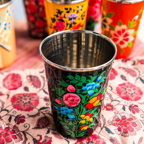 Decorative metal cups with floral patterns on a floral tablecloth