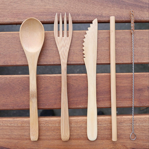 reusable sustainable bamboo cutlery set with fork, spoon, knife and straw on top of a wood table