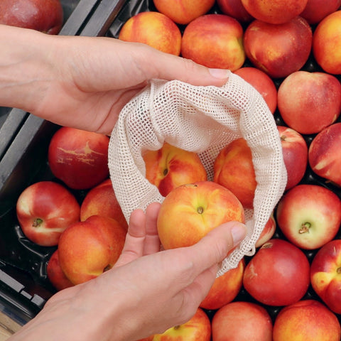 reusable mesh bag being shown buying peaches in a market