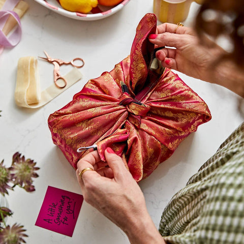 gift wrapped in red and gold sari gift wrap on a white surface