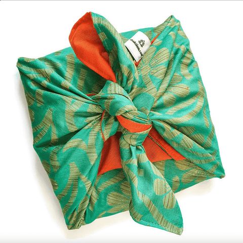 gift wrapped in green and orange sari gift wrap on a white surface
