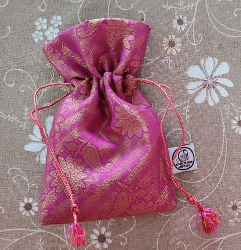 Pink sari gift bag with drawstring on beige floral surface