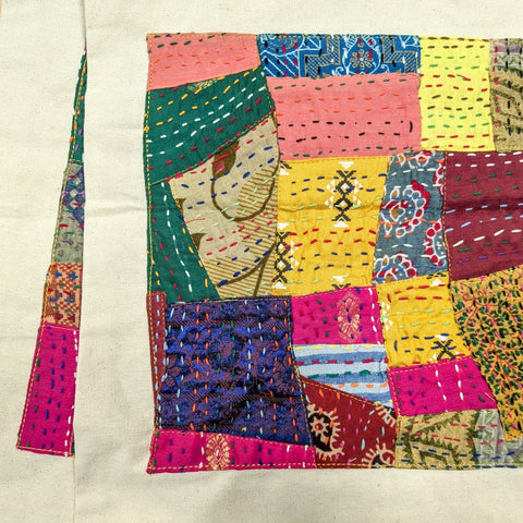 zoomed in on pile of sari patchwork tote bags with kantha stitching on a light wooden surface