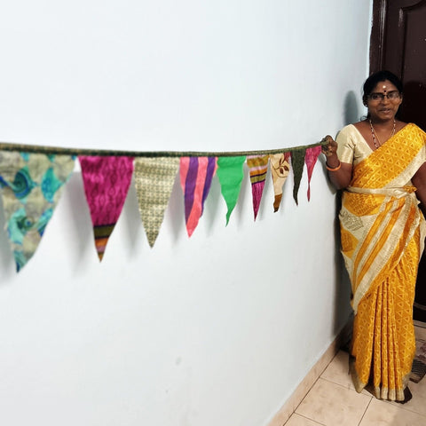 Upcycled sari flags, reusable sari bunting held up by artisan