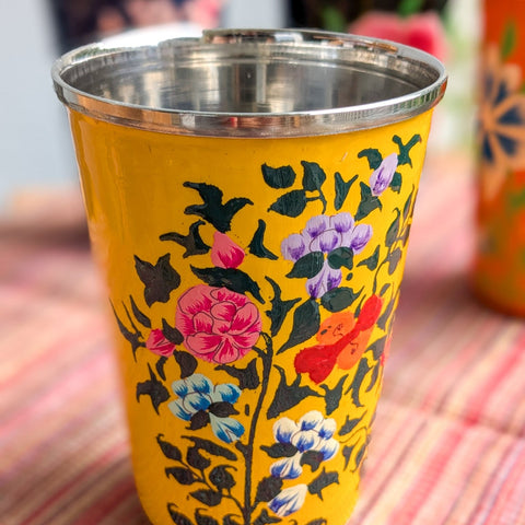 Yellow cup with floral design on a patterned surface